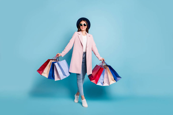Full size photo of lovely funny girl on her weekends go shopping buy presents souvenirs wear vintage season coat denim jeans eyeglasses eyewear isolated over blue background - Foto, immagini
