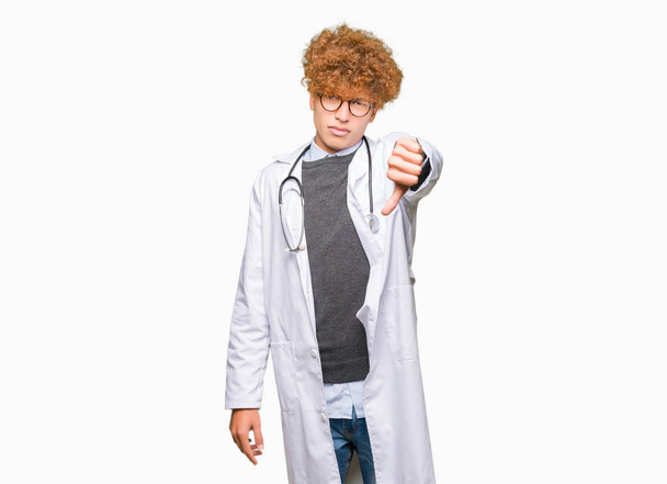 Nuori komea lääkäri mies yllään lääketieteellinen takki näyttää onneton ja vihainen osoittaa hylkääminen ja negatiivinen peukalot alas ele. Huono ilme
. - Valokuva, kuva