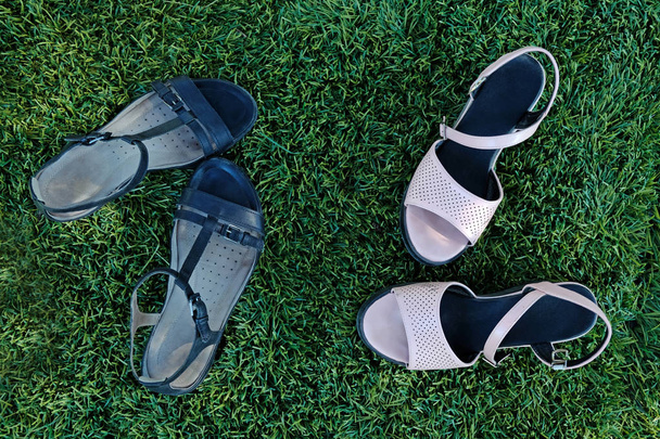 Black and pink women's sandals on the grass top view. Summer women's shoes in the park on a green lawn. - Photo, Image