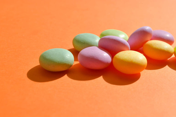 runde farbige Bonbons liegen in einem Bündel auf orangefarbener Farbe, mit Copyspace auf Sonnenschein, Nahaufnahme, Nahaufnahme - Foto, Bild
