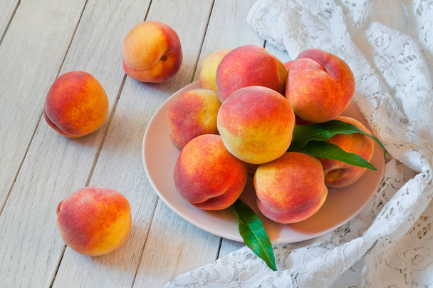 Fresh organic peaches in a plate on a white wooden table - Photo, Image