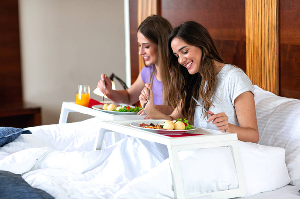 Beautiful young women eating in bed  - 写真・画像