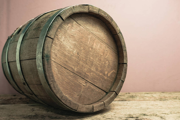 Hermoso barril de madera sobre una mesa de roble viejo y fondo de pared rojo
. - Foto, Imagen