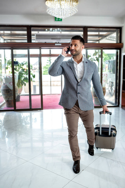 Businessman dragging his luggage and entering a hotel - Фото, зображення