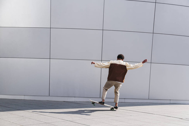Afro skateboarder outdoors doing trick on white - Photo, Image