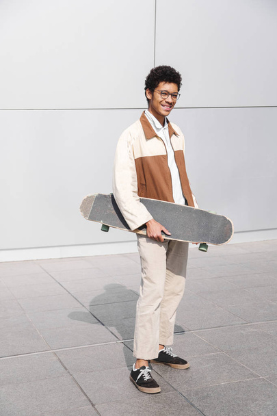 African american skater holds skateboard in hands - Photo, image