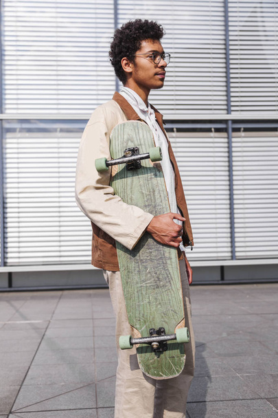 Skateboarder stands with his skateboard in city - Φωτογραφία, εικόνα