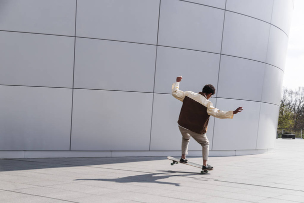 Afro skateboarder outdoors doing trick on white - Foto, imagen