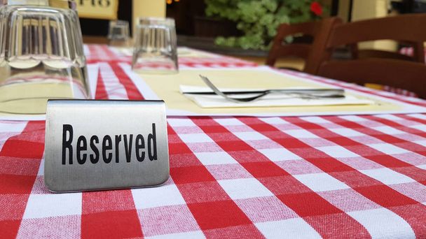 Reserved table in outdoor cafe, metal tag on table restaurant reservation. - Photo, Image