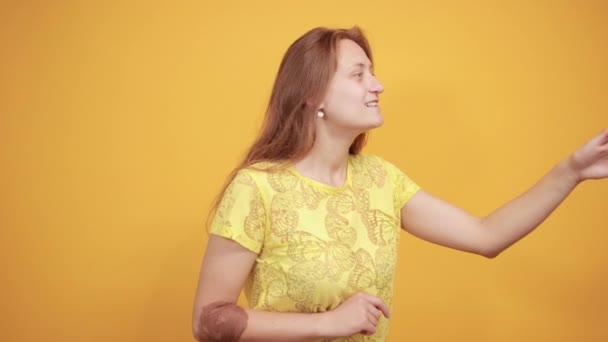 brunette girl in yellow t-shirt over isolated orange background shows emotions - Imágenes, Vídeo