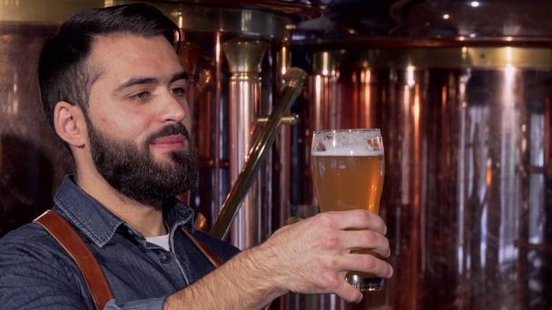 Handsome bearded brewer enjoying smell and taste of delicious craft beer - Photo, Image