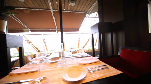 Tavolo decorato per due persone con vetreria e sedie rosse in una sala ristorante
 - Filmati, video