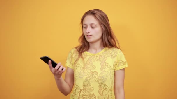 brunette girl in yellow t-shirt over isolated orange background shows emotions - Filmati, video