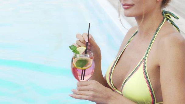 Ritaglio di una donna sexy in bikini sorseggiando un cocktail vicino alla piscina
 - Foto, immagini