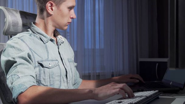 Deslizando tiro de um freelancer do sexo masculino trabalhando tarde da noite usando dois computadores
 - Foto, Imagem
