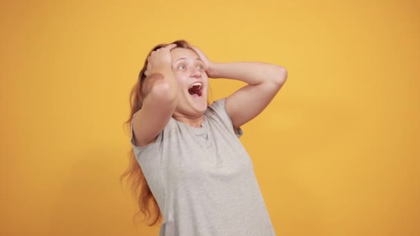 morena chica en gris camiseta sobre aislado naranja fondo muestra emociones
 - Metraje, vídeo