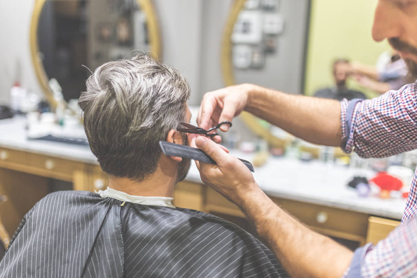Man in barber chair, hairdresser styling his hair. - Фото, зображення