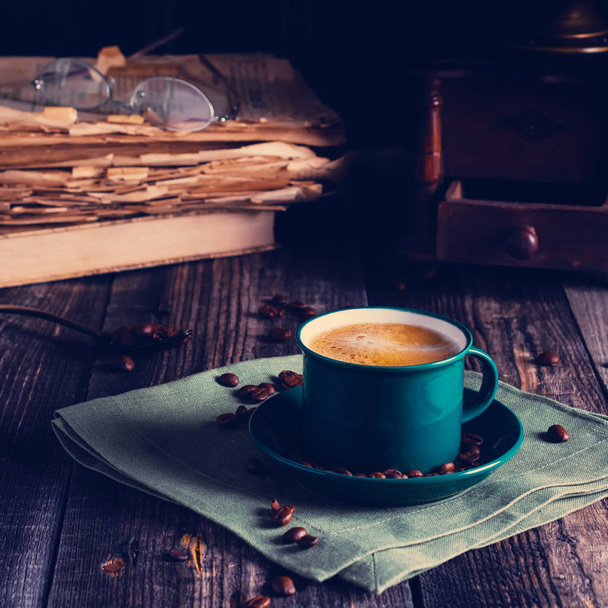 Cafe background with a green cup of espresso coffee standing on a linen napkin with a retro coffee grinder old book. Retro style Nashville. Tonted image. Square image. - Zdjęcie, obraz