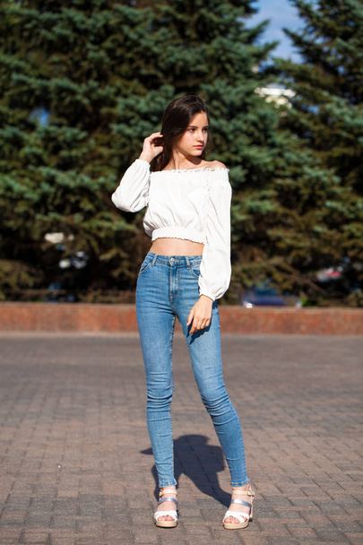 Pretty stylish brunette girl in blue jeans and white blouse  - Foto, Imagem