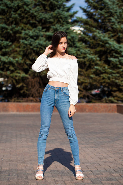 Pretty stylish brunette girl in blue jeans and white blouse  - Photo, image