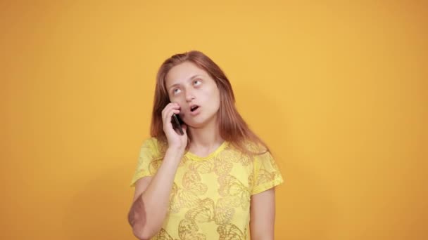 brunette girl in yellow t-shirt over isolated orange background shows emotions - Felvétel, videó