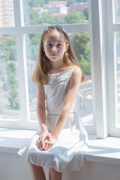 Little girl in white dress.Little girl in a white dress by the window - Фото, зображення