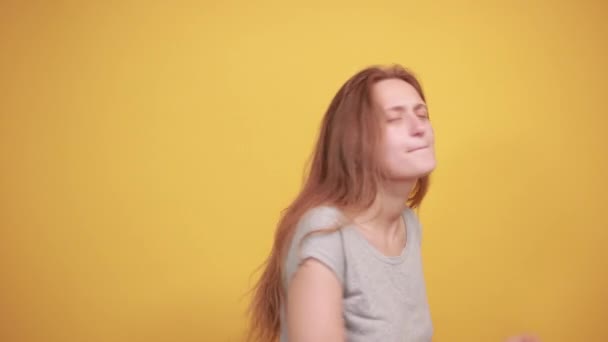 brunette girl in gray t-shirt over isolated orange background shows emotions - Felvétel, videó