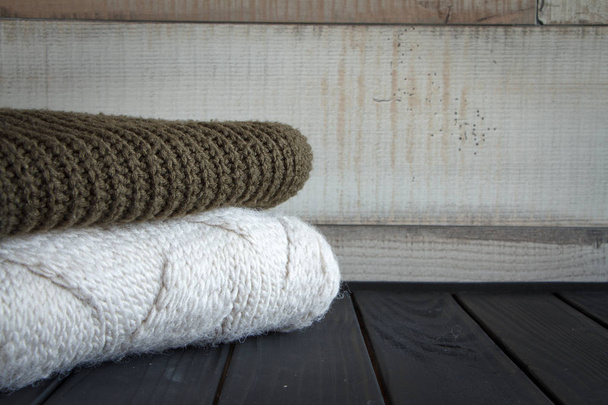 Close-up shot of two knitted from natural wool sweaters, on a black wooden table, selective focus - 写真・画像