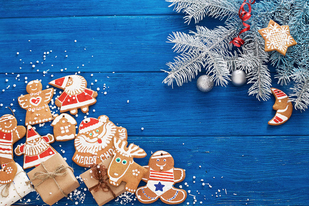 fir branches, Christmas gingerbread cookies, decorations and gifts on a blue wooden background. - Foto, afbeelding