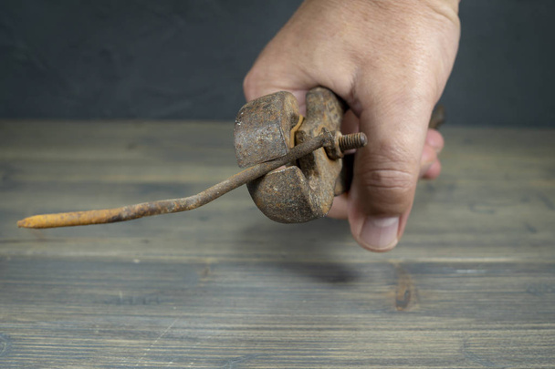 Мужская рука держит ржавые рукоятки и изогнутый ноготь
 - Фото, изображение