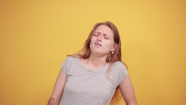 brünettes Mädchen im grauen T-Shirt über isoliertem orangefarbenem Hintergrund zeigt Emotionen - Filmmaterial, Video