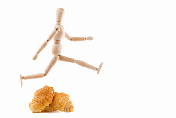 Wood dummy  jumping croissant on white background - Photo, Image