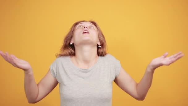 brunette girl in gray t-shirt over isolated orange background shows emotions - Filmagem, Vídeo