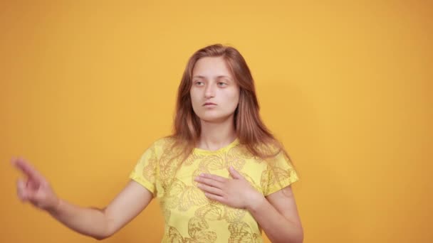 Brünettes Mädchen in gelbem T-Shirt über orangefarbenem Hintergrund zeigt Emotionen - Filmmaterial, Video