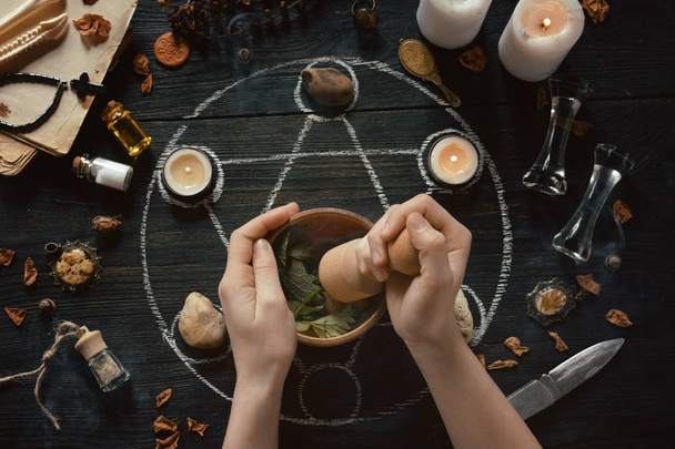 Womens hands make love potion on pentagram circle with candles, stones and old books on witch table. Occult, esoteric or divination concept. Mystic, Halloween and vintage background - Foto, Bild