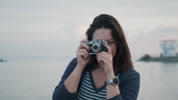 ritratto di una ragazza con una macchina fotografica retrò. giovane donna scatta foto su una macchina fotografica vintage in riva al mare
 - Filmati, video