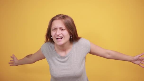 brunetka v šedém tričku nad ojedinělým oranžovým pozadím vykazuje emoce - Záběry, video