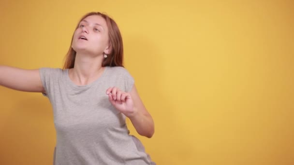brunette tyttö harmaa t-paita yli eristetty oranssi tausta osoittaa tunteita
 - Materiaali, video
