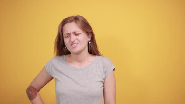 μελαχρινή κορίτσι σε γκρίζο t-shirt πάνω από απομονωμένο πορτοκαλί φόντο δείχνει τα συναισθήματα - Πλάνα, βίντεο