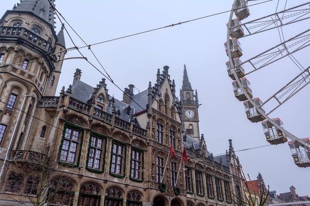 Reuzenrad in het centrum van Gent in de buurt van het gotische oude post kantoorgebouw in mistig winter Morning tegen Cold Grey Sky. - Foto, afbeelding