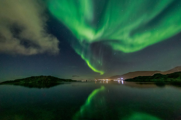 Green Northern lights reflecting in the lake with mountains and  - Photo, Image