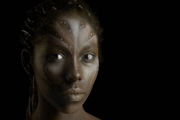 Καλλιτεχνική φωτογραφία της Αφρικανικής γυναίκας με φυλετικές εθνοτικές ζωγραφιές στο πρόσωπό της - Φωτογραφία, εικόνα