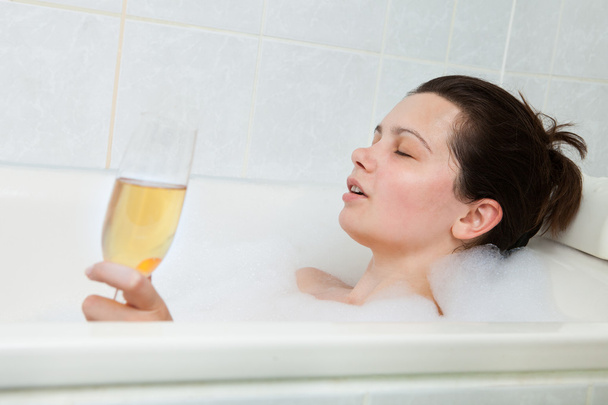 Woman in bathtub drinking champagne - 写真・画像