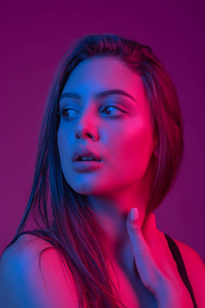 Closeup gezicht van mooie brunete vrouw in neon licht rood en blauw. - Foto, afbeelding