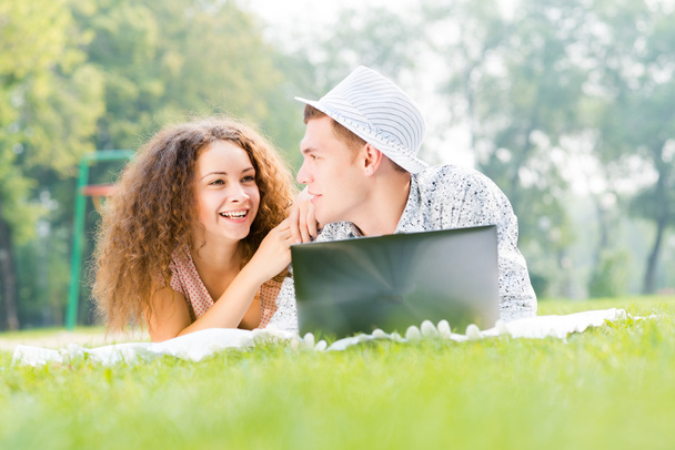 pár együtt egy parkban fekvő, laptop - Fotó, kép