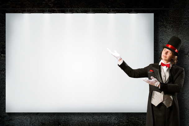 magician in top hat and tie points to the banner - 写真・画像