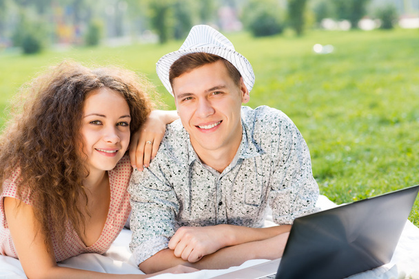 couple lying together in a park with laptop - Fotoğraf, Görsel