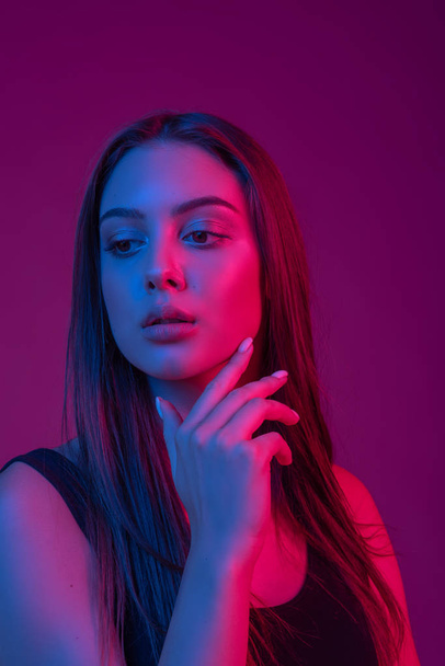Closeup face of beautiful brunete woman in neon light red and blue. - Foto, immagini