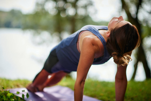 Vue arrière de brune caucasienne dans la pose de yoga Planche vers le haut. Nature à l'extérieur d'été
. - Photo, image