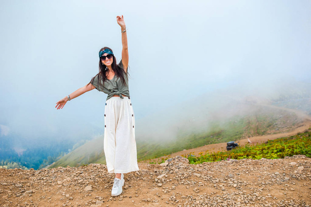 Hermosa joven feliz en las montañas en el fondo de la niebla - Foto, Imagen